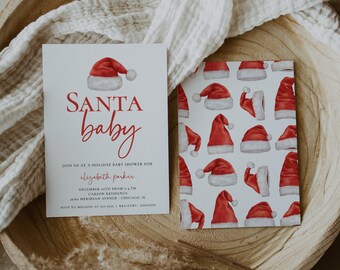May include: A white card with red text that reads "SANTA baby" and details for a holiday baby shower for Elizabeth Parker. The card is on a wooden surface with a white cloth and a dried plant.