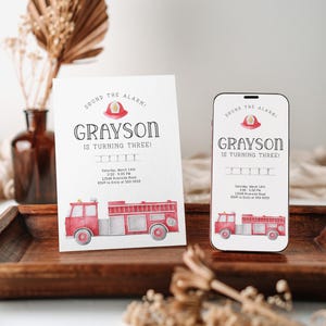 Puede incluir: Una tarjeta de invitaci&oacute;n rectangular blanca y una pantalla de tel&eacute;fono inteligente que muestra el mismo dise&ntilde;o: un cami&oacute;n de bomberos rojo en acuarela, un casco de bombero y el texto "SOUND THE ALARM! GRAYSON IS TURNING THREE!" con los detalles del evento.