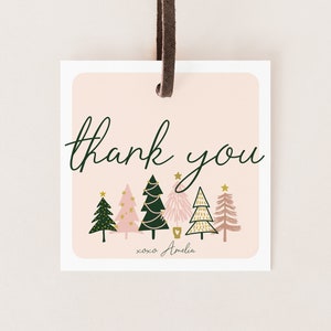 以下が含まれることがあります： ピンクとグリーンのクリスマスギフトタグ。スタイリッシュなクリスマスツリーが並んでおり、「thank you xoxo Amelia」の文字が書かれています。
