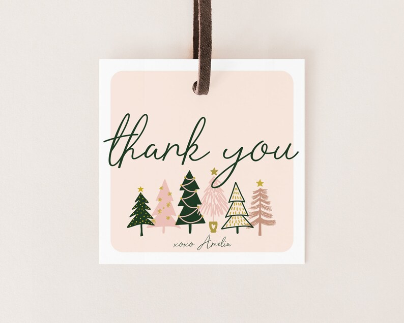 以下が含まれることがあります： ピンクとグリーンのクリスマスギフトタグ。スタイリッシュなクリスマスツリーが並んでおり、「thank you xoxo Amelia」の文字が書かれています。
