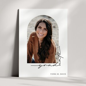 May include: A graduation announcement featuring a smiling person in a brown sweater, framed by an arch. The word "grad" is written in cursive, along with the name "Fiona M. Davis" at the bottom.