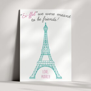 May include: A white canvas print with a teal Eiffel Tower illustration and the text "Ei-ffel" we were meant to be friends!" in pink cursive. The text "LOVE, AUDREY" is also in pink cursive at the bottom of the print.