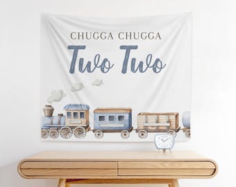 May include: A white banner with blue text that reads "Chugga Chugga Two Two". A watercolor illustration of a blue train with a brown boxcar is at the bottom of the banner.