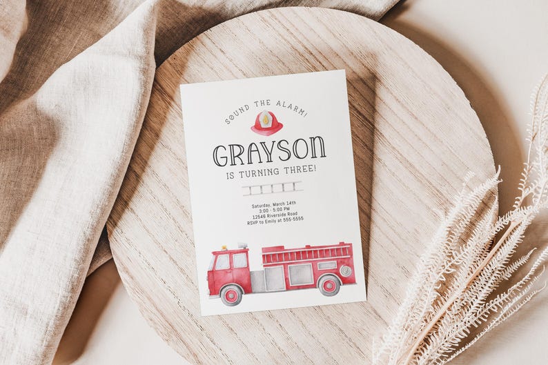 A birthday invitation with a red fire truck and a firefighter helmet in minimalist design. The text reads 'Sound the alarm! Grayson is turning three!