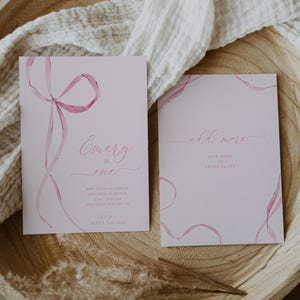 May include: Pink invitation with watercolor ribbons and the text "Emery is one" and details for a birthday party. A second card says "add more" with space to write in.