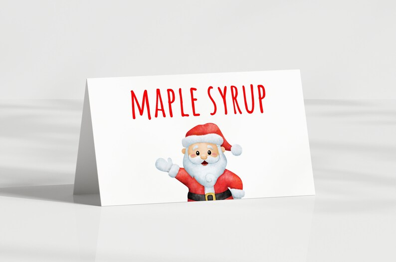 May include: A white card with red text that says "MAPLE SYRUP". A cartoon Santa Claus is in the bottom right corner of the card.