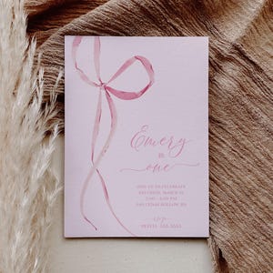 May include: Pink invitation with a watercolor illustration of a pink ribbon bow. The text reads "Emery is one" and includes details for a birthday party on Saturday, March 15th from 2:00 to 4:00 PM at 648 Cedar Hollow Rd. The invitation also includes the name Olivia and a phone number.