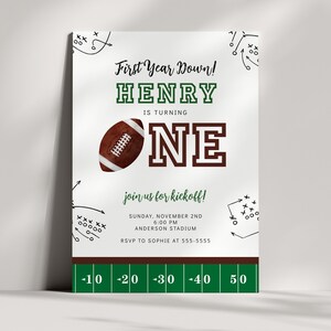 May include: A green and white football-themed first birthday party invitation for a boy named Henry. The invitation features a football, a green and white football field, and the text "First Year Down! Henry is turning One. Join us for kickoff! Sunday, November 2nd, 6:00 PM, Anderson Stadium. RSVP to Sophie at 555-5555."