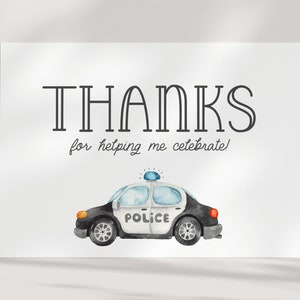 May include: A white thank you card with black text that says "THANKS for helping me celebrate!" and a watercolour illustration of a black and white police car with a blue light on top.