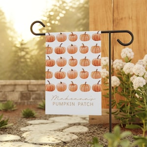 May include: A white garden flag featuring a pattern of orange pumpkins. The flag has the text "Makenna's PUMPKIN PATCH" in a script font. The flag is displayed on a black metal garden stake in an outdoor setting.