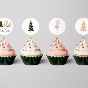 May include: Four cupcakes decorated with pink and white frosting and gold sprinkles. Each cupcake has a round paper topper with a Christmas tree or ballerina design. One topper says "Tutu Cute".