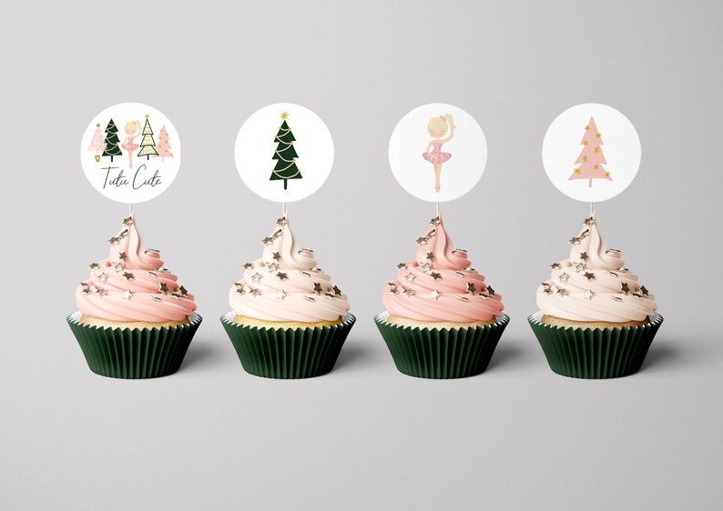 May include: Four cupcakes decorated with pink and white frosting and gold sprinkles. Each cupcake has a round paper topper with a Christmas tree or ballerina design. One topper says "Tutu Cute".