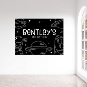 May include: Black and white space-themed birthday party backdrop with the text "Bentley's 4th Birthday" and illustrations of planets, stars, a rocket ship, and an astronaut.