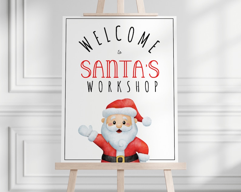 May include: A sign on an easel with the words "WELCOME to SANTA'S WORKSHOP" in black and red. The sign features a watercolour illustration of Santa Claus in a red suit and hat, with a white beard and gloves, at the bottom.