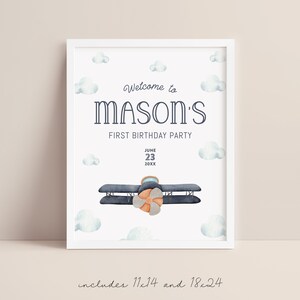 Może przedstawiać: Oprawiony wydruk z białym obramowaniem zawiera napis "Welcome to Mason's First Birthday Party" w granatowym skrypcie. Akwarelowy samolot i chmury zdobią wydruk. Data "June 23 20XX" jest r&oacute;wnież uwzględniona.