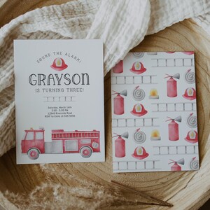 A birthday invitation with a red fire truck and a firefighter helmet. The text reads 'Sound the alarm! Grayson is turning three!  Backside features graphics of fire extinguisher, ladder, hat and hose.
