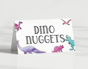 Puede incluir: Una tarjeta blanca con el texto "Dino Nuggets" en letras negras. La tarjeta está decorada con siluetas de dinosaurios de colores.