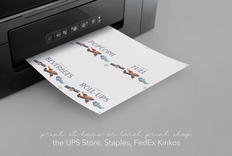 May include: A black printer outputting a white sheet of paper featuring printed labels with airplane illustrations and text including POPCORN, BEVERAGES, FUEL, and ROLL-UPS. The labels are arranged in rows with small blue and orange airplane graphics.