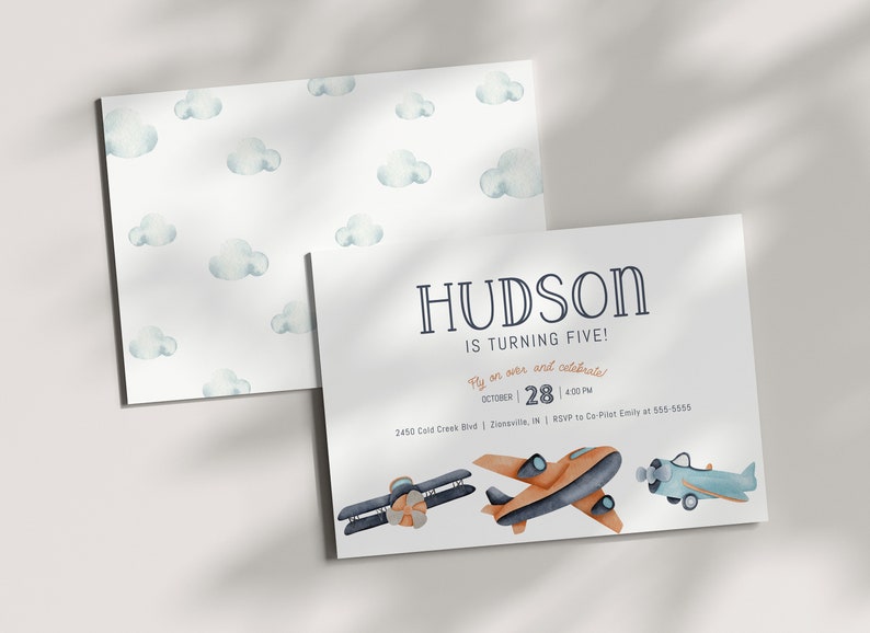 May include: A white invitation with blue and orange aeroplanes and clouds. The text reads "HUDSON IS TURNING FIVE! Fly on over and celebrate! October 28 | 4:00 PM 2450 Cold Creek Blvd | Zionsville, IN | RSVP to Co-Pilot Emily at 555-0550"