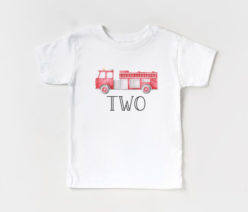 May include: A white short-sleeve t-shirt featuring a watercolor-style red fire truck graphic centered on the chest. Below the fire truck, the word TWO is printed in a bold, black, sans-serif font. The design is simple and centered on the shirt.