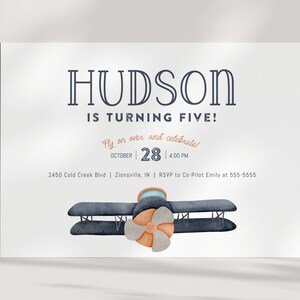 Może przedstawiać: Biała karta zaproszenia z napisem "HUDSON IS TURNING FIVE!" w kolorze granatowym. Karta zawiera tekst "Fly on over and celebrate!" oraz datę 28 października, 16:00. Na dole znajduje się akwarelowa ilustracja dwupłatowca.
