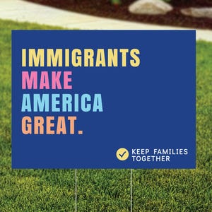 May include: A blue yard sign with the words "IMMIGRANTS MAKE AMERICA GREAT" in yellow, pink, blue, and orange. The sign also includes the text "KEEP FAMILIES TOGETHER" with a checkmark.