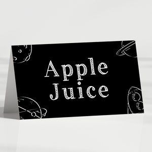 May include: Black and white sign with the text "Apple Juice" in a decorative font. The sign is decorated with white drawings of planets and spaceships.