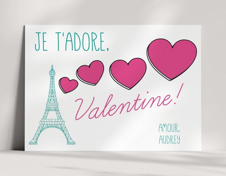 May include: A white card with a teal Eiffel Tower, pink hearts, and the text "Je t'adore, Valentine! Amour, Audrey".