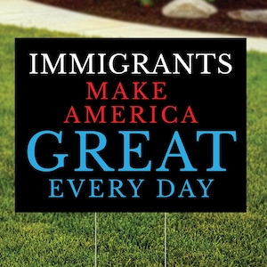 May include: Black yard sign with white text that reads "Immigrants Make America Great Every Day". The words "Make America Great" are in red.