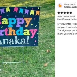May include: A black chalkboard sign with colourful lettering that reads "Happy Birthday Anaka!" The sign is decorated with colourful flags and confetti.
