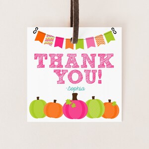 May include: Thank you tag with a pink and white pumpkin design. The tag has a string attached and says "Thank You! -Sophia" with a banner of colorful flags at the top.