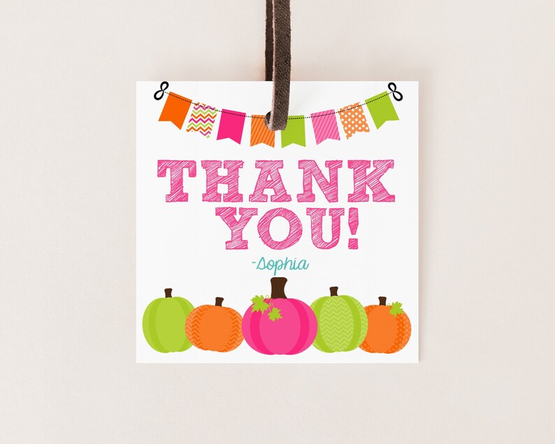 May include: Thank you tag with a pink and white pumpkin design. The tag has a string attached and says "Thank You! -Sophia" with a banner of colorful flags at the top.