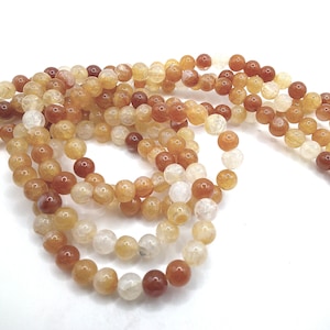 May include: A strand of round, translucent beads in shades of orange, yellow, and white. The beads are made of agate and have a natural, slightly rough texture.