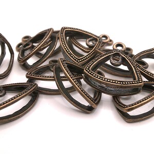May include: A group of antique gold-toned metal triangle pendant frames with a decorative beaded edge. The frames are open on two sides and have a loop at the top for hanging.