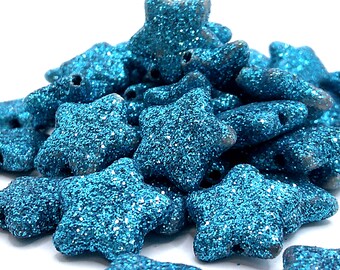 May include: A pile of teal blue glitter star-shaped beads. The beads are made of a soft, textured material and have a hole in the center for stringing.