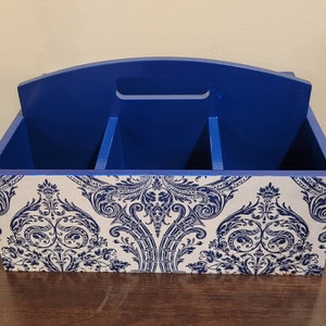 May include: A blue wooden organizer with three compartments. The organizer has a white and blue damask pattern on the front.