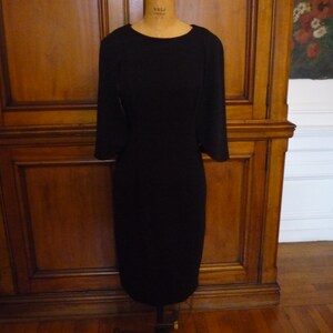 May include: A black, knee-length dress with a simple, fitted silhouette and three-quarter sleeves.