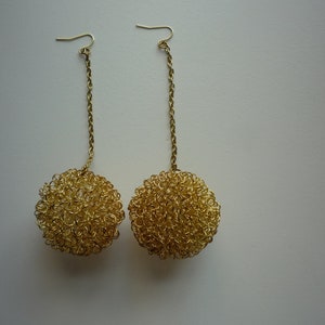 May include: A pair of gold earrings with dangling round, textured, gold balls.