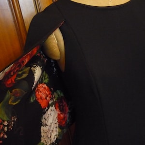 May include: Black dress with a floral print lining. The lining is visible at the shoulder seam.