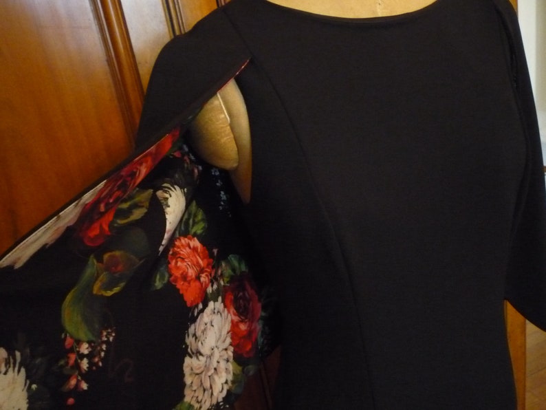 May include: Black dress with a floral print lining. The lining is visible at the shoulder seam.