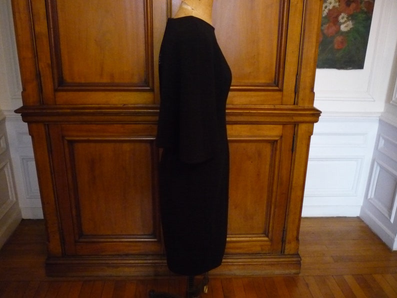 May include: A black knee-length dress with a round neckline and three-quarter sleeves.