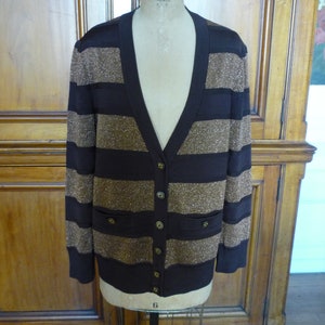 May include: A brown and gold striped cardigan with a v-neck and button closure. The cardigan has two pockets on the front.