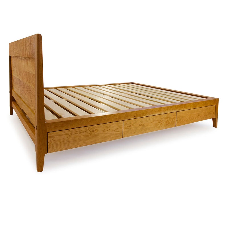 Peut inclure: Un cadre de lit en bois avec une t&ecirc;te de lit &agrave; lattes et trois tiroirs en dessous. Le cadre est en bois clair avec une finition naturelle.