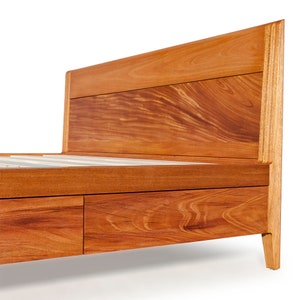 Peut inclure: Un cadre de lit en bois avec une t&ecirc;te de lit et deux tiroirs. Le cadre est en bois brun rouge&acirc;tre riche avec un grain de bois naturel.