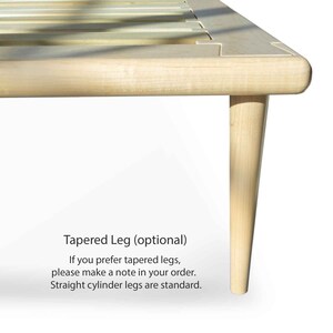 May include: Close-up of a wooden bed frame with tapered legs. The text "Tapered Leg (optional)" is visible below the frame. "If you prefer tapered legs, please make a note in your order. Straight cylinder legs are standard." is also visible.