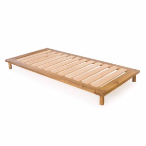 May include: A wooden slat bed frame with a natural wood finish and four legs. The frame is made of solid wood and has a simple, modern design.