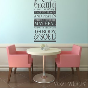 May include: A vinyl wall decal with a quote that reads "Everybody needs beauty as well as bread, places to play in and pray in, where nature may heal and give strength to body and soul." The decal is shown on a light blue wall above a table and chairs.