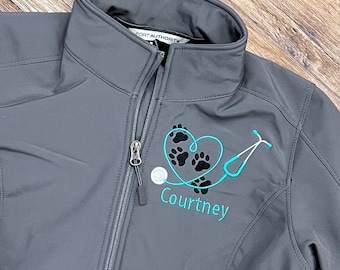 May include: Gray soft-shell jacket with a teal embroidered design of a stethoscope and paw prints forming a heart. The name "Courtney" is embroidered below the design.