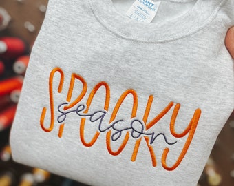 May include: A gray sweatshirt with the text "Spooky Season" embroidered in orange and purple.