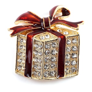 May include: A gold-tone gift box brooch with a red bow and clear rhinestones. The box is decorated with red enamel.